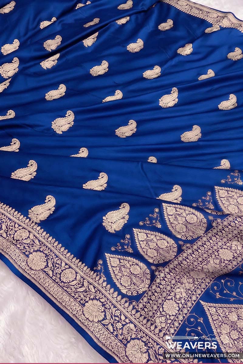 A royal blue Banarasi silk saree with intricate gold zari embroidery, featuring small paisley motifs and a wide decorative border.