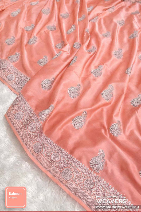 A salmon pink Banarasi silk saree with silver paisley and border motifs, draped on a white textured surface. A brand label for 'Weavers Online' and a color label 'Salmon' are visible.