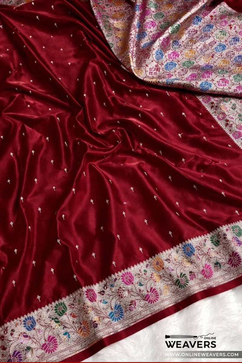 A close-up of a rich maroon red mashru silk saree, likely a Banarasi saree, featuring delicate silver zari embroidery, a colorful floral border, and a matching patterned inner lining-KL112